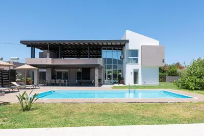 a house with a swimming pool in front of it at Marane Deluxe House in Ialyssos