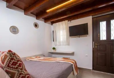 a bedroom with a bed and a flat screen tv at Heritage Luxury Suites in Líndos