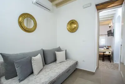 a living room with a couch with pillows and a mirror at Heritage Luxury Suites in Líndos