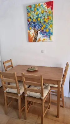 a wooden table and chairs with a painting on the wall at Kozas Art House, Symi in Symi