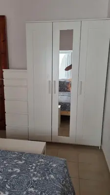 a bedroom with a large white cabinet with a mirror at Kozas Art House, Symi in Symi