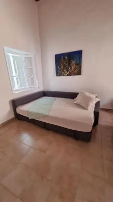 a large bed in a room with two windows at Kozas Art House, Symi in Symi