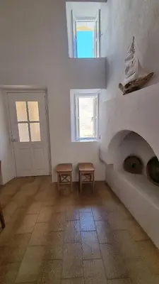 a white room with a fireplace and a floor at Kozas Art House, Symi in Symi