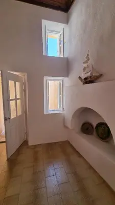 a white room with a fireplace and a door at Kozas Art House, Symi in Symi