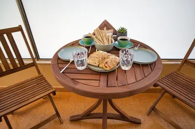 a wooden table with a plate of food and two chairs at Casa di Flora Luxurious Apartment in Rhodes in Rhodes Town