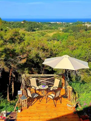 a deck with a table and chairs and an umbrella at Villa René in Koskinou