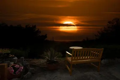 a wooden bench sitting in front of a sunset at Villa René in Koskinou