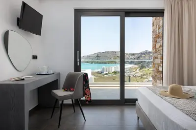 a bedroom with a bed and a desk and a window at Alindo Villa I in Líndos