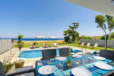 a patio with a table and chairs and a swimming pool at Villa Rhodes Sea View by Villa Plus in Ixia