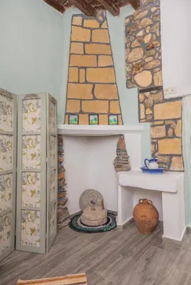 a room with a fireplace and a stone wall at Philoxenia traditional house in Pastida