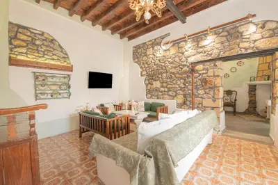 a living room with a large stone wall at Philoxenia traditional house in Pastida