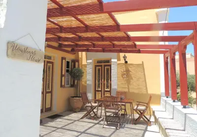 a patio with a table and chairs under a wooden pergola at Aloustina's House in Symi