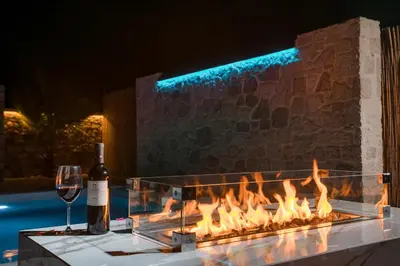 a wine glass and a bottle of wine next to a fireplace at Le Ialyse Luxury Villa in Ialyssos