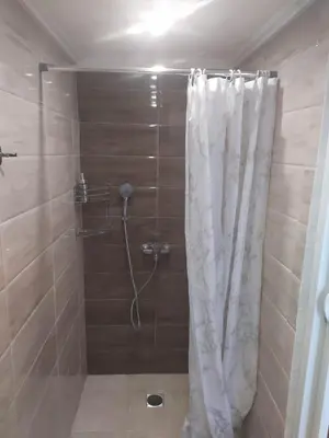 a shower with a white shower curtain in a bathroom at K Farm House in Kalavárda