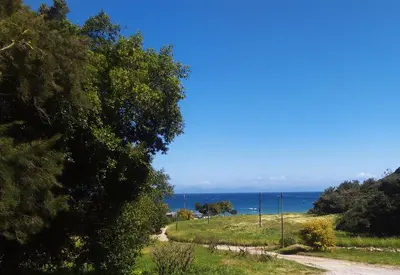 a dirt road with the ocean in the background at K Farm House in Kalavárda