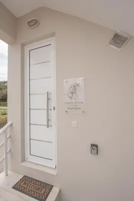 a white door in a white room with a rug at Inconceptual apartment in Paradeísion