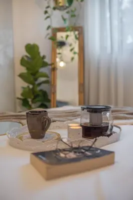 a table with a candle and a cup and a book at Inconceptual apartment in Paradeísion