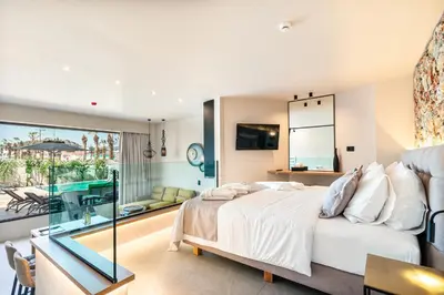 a bedroom with a large bed and a balcony at Pathos SeaSide Suites in Faliraki