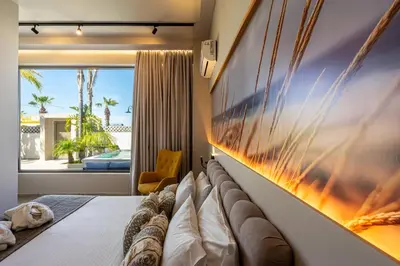 a bedroom with a large painting on the wall at Pathos SeaSide Suites in Faliraki