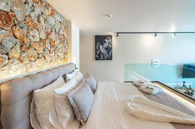 a bedroom with a stone wall and a bed with pillows at Pathos SeaSide Suites in Faliraki