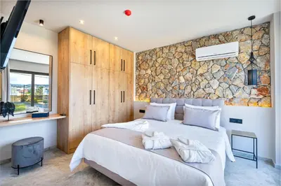 a bedroom with a large bed and a stone wall at Pathos SeaSide Suites in Faliraki