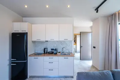 a kitchen with white cabinets and a black refrigerator at Pathos SeaSide Suites in Faliraki
