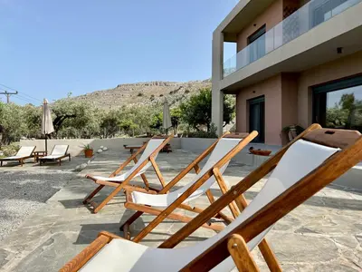 a group of lawn chairs sitting on a patio at PETRA RESIDENCES IN LINDOS in Líndos