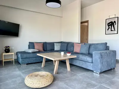 a living room with a blue couch and a table at PETRA RESIDENCES IN LINDOS in Líndos