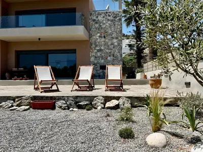 two lounge chairs sitting in front of a house at PETRA RESIDENCES IN LINDOS in Líndos