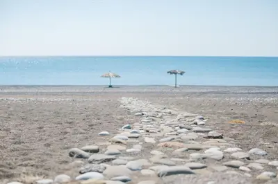 a group of rocks on a beach with umbrellas at Ktima Tzaneti - Coastal Farmhouse in Lachania