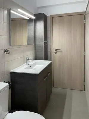 a bathroom with a sink and a wooden door at Ktima Tzaneti - Coastal Farmhouse in Lachania