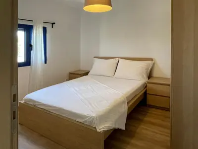 a bedroom with a bed with white sheets and a window at Ktima Tzaneti - Coastal Farmhouse in Lachania