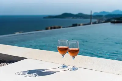 two glasses of wine sitting next to a swimming pool at Diamond Hill Villa in Koskinou