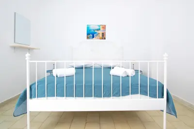 a white crib in a white room with a blue bed at CHAMBRE BLANCHE in Ialyssos