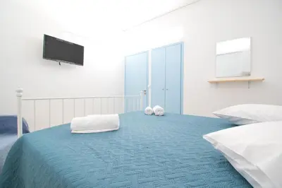 a bedroom with two beds and a flat screen tv at CHAMBRE BLANCHE in Ialyssos