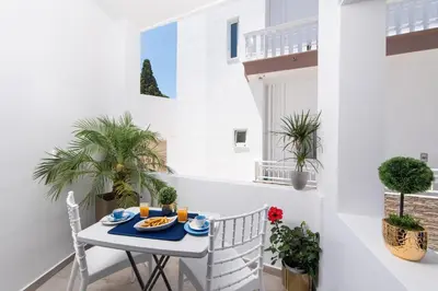 a small table and chairs on a balcony with plants at Antonia's Apartments in Archangelos
