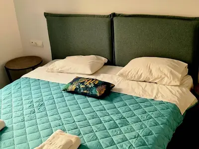 a bed with a green head board and two pillows at Rhodes Comfort Luxury Apartment in Rhodes Town
