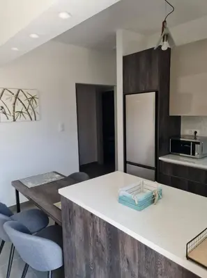 a kitchen with a table and some blue chairs at Rhodes Comfort Luxury Apartment in Rhodes Town