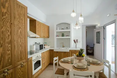 a kitchen with wooden cabinets and a table with chairs at AENAON in Archangelos