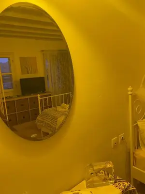 a mirror on a yellow wall in a room at villa Elpiniki Tilos in Megálon Choríon