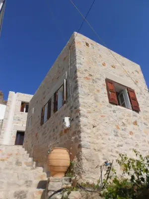 a stone building with two windows and a pot at villa Elpiniki Tilos in Megálon Choríon