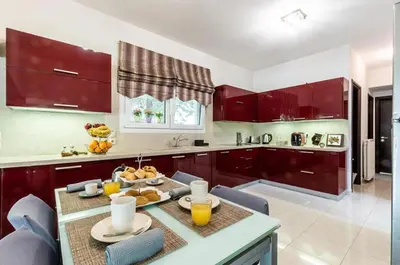 a kitchen with red cabinets and a table with fruit on it at GGA Albatross Villa in Afantou