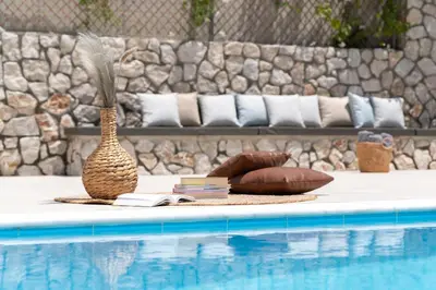a vase and books on a table next to a swimming pool at GGA Albatross Villa in Afantou