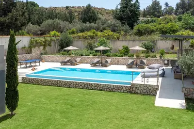 a swimming pool in a yard with chairs and umbrellas at GGA Albatross Villa in Afantou