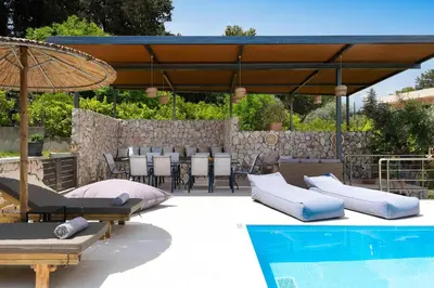 a patio with pillows and an umbrella next to a pool at GGA Albatross Villa in Afantou