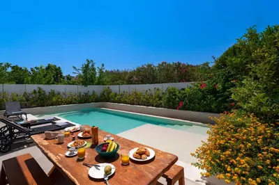 a table with food on it next to a swimming pool at Thalassa Luxury Villa in Ialyssos