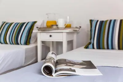 a magazine laying on a bed with a table and a bed sidx sidx at Thalassa Luxury Villa in Ialyssos