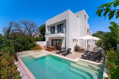 a villa with a swimming pool in front of a house at Thalassa Luxury Villa in Ialyssos