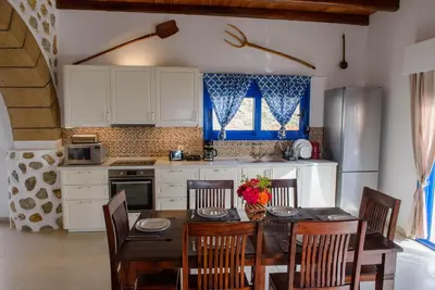 a kitchen with a table and chairs and a kitchen with white cabinets at Villa Leonardo in Archangelos