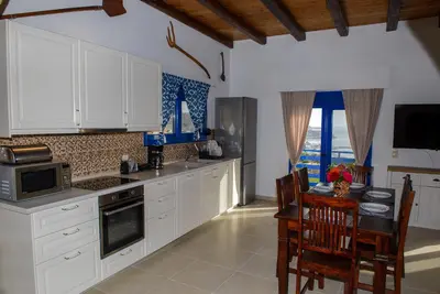 a kitchen with white cabinets and a table and chairs at Villa Leonardo in Archangelos